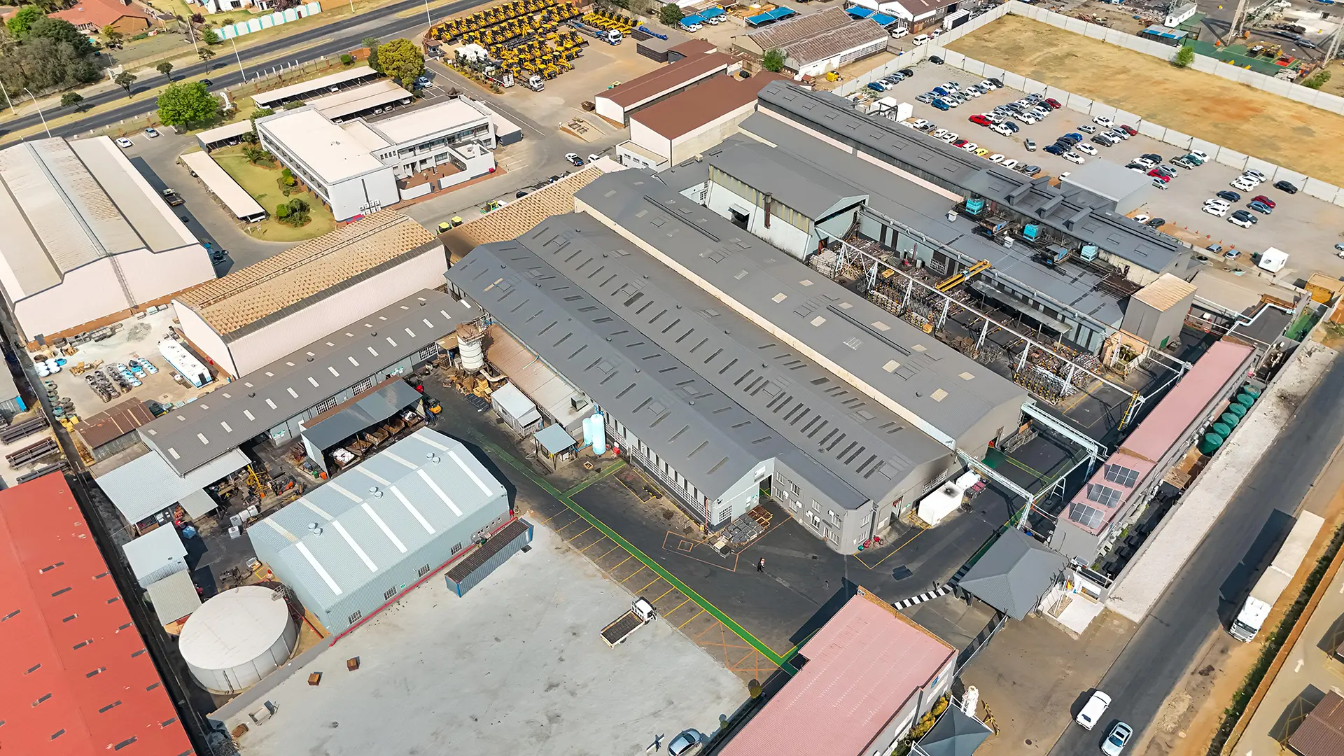 Aerial view of a sprawling industrial complex featuring multiple large grey-roofed buildings, ideal for professional roof refurbishments.