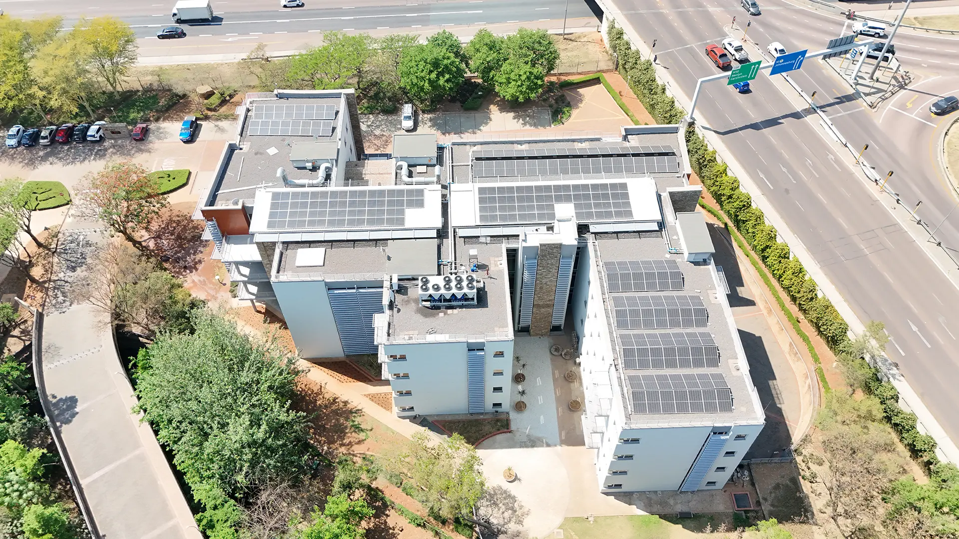 Overhead shot of a large building complex featuring extensive solar panel arrays on its roofs, highlighting professional roof refurbishments.